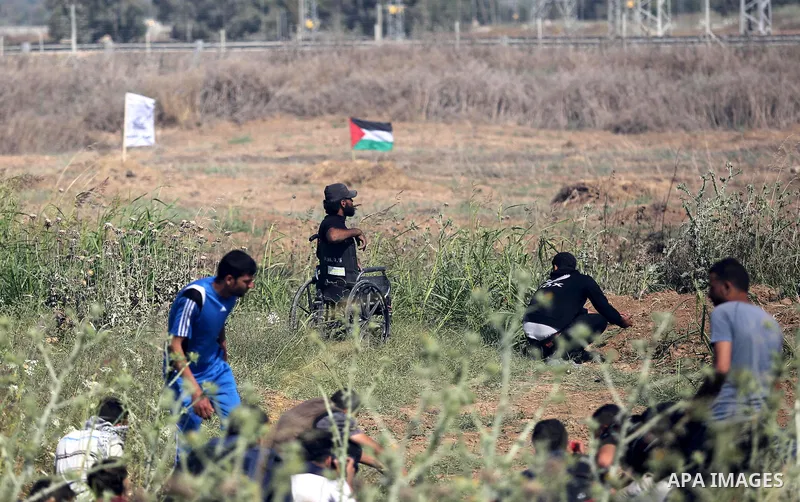 (FILES) This file photo taken on May 19, 2017 shows A handicapped Palestinian protester Ibraheem Abu Thuraya, 29 tries to run from a tear gas fired by Israeli security forces during clashes following a protest against th...