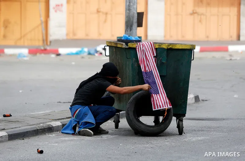 Palestinian protesters burn a representation of U.S. flag during clashes with Israeli security forces, at a protest as Palestinians call for a "Day of Rage" in response to U.S. President Donald Trump's recognition of Jer...