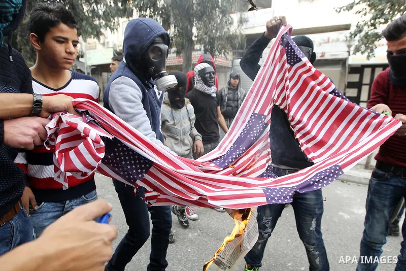 Palestinian protesters burn a representation of U.S. flag during clashes with Israeli security forces, at a protest as Palestinians call for a "Day of Rage" in response to U.S. President Donald Trump's recognition of Jer...