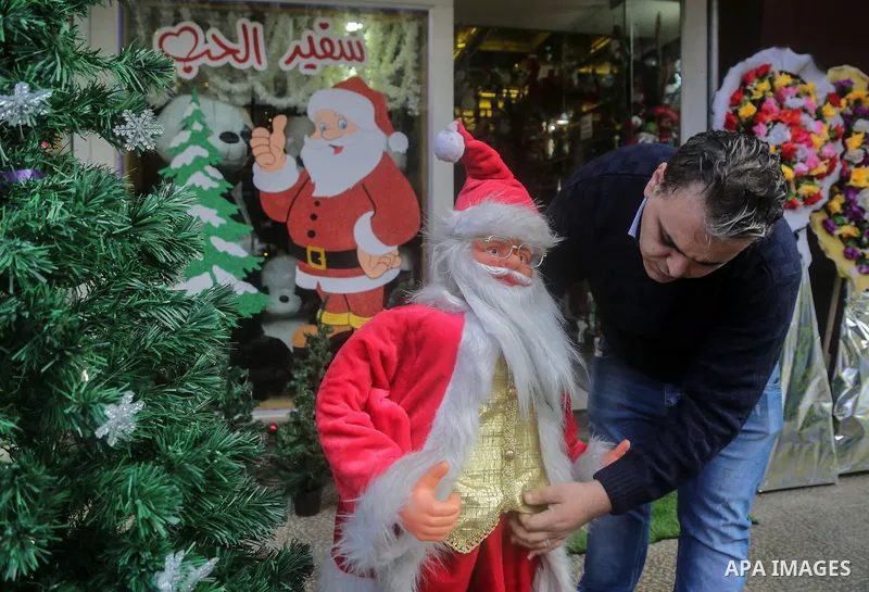A Palestinian shop keeper dresses plastic models outfitted as Santa Claus (or Father Christmas) outside his shop in Gaza City on December 25, 2017. Photo by Mohammed Dahman