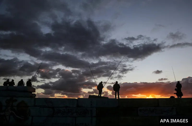 Palestinians enjoy during sunset at Gaza seaport on December 25, 2017. Photo by Mohammed Dahman