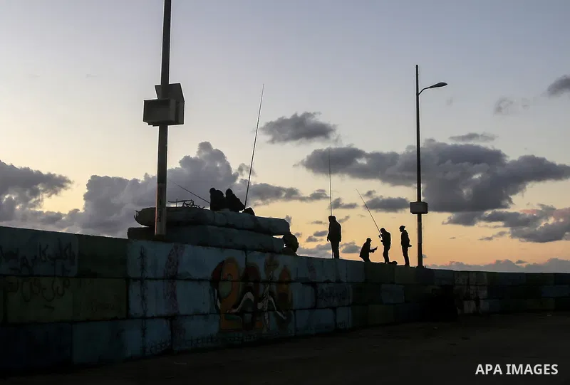 Palestinians enjoy during sunset at Gaza seaport on December 25, 2017. Photo by Mohammed Dahman