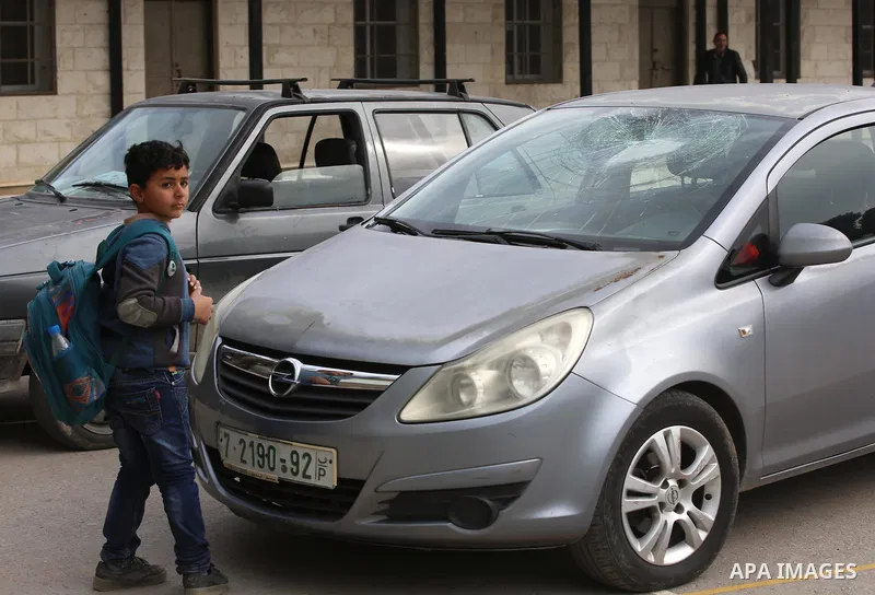 A Palestinian boy looks at a car attacked by Israeli settlers in the West Bank village of Burin, near Nablus, on December 28, 2017. Photo by Ayman Ameen