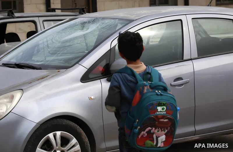 A Palestinian boy looks at a car attacked by Israeli settlers in the West Bank village of Burin, near Nablus, on December 28, 2017. Photo by Ayman Ameen