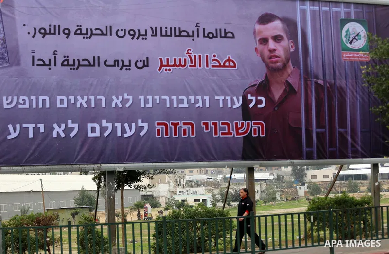 A Palestinian man walks past a billboard bearing a portrait of slain Israeli soldier Oron Shaul in Gaza City on December 29, 2017. The writing in Arabic reads: ''As long as our heroes don't see freedom and light: This ca...