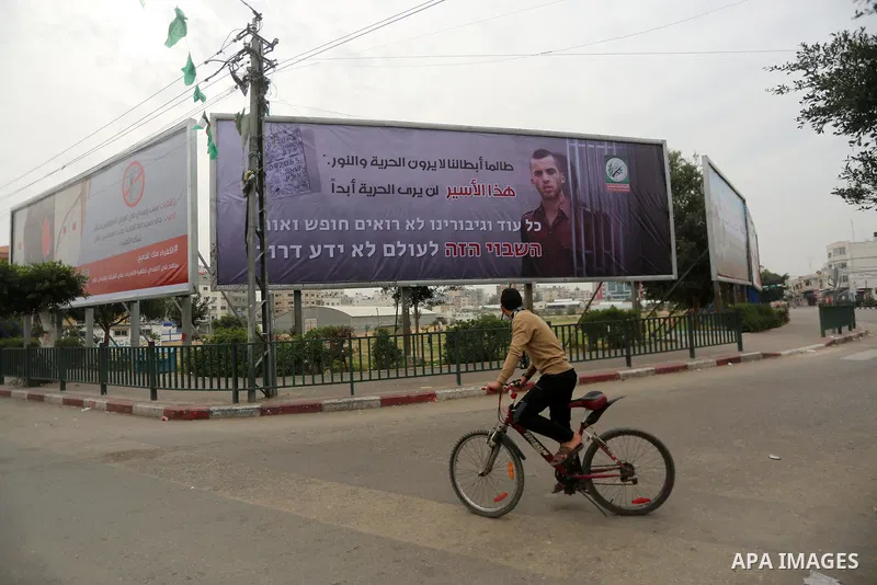 A Palestinian boy rides his bicycle past a billboard bearing a portrait of slain Israeli soldier Oron Shaul in Gaza City on December 29, 2017. The writing in Arabic reads: ''As long as our heroes don't see freedom and li...