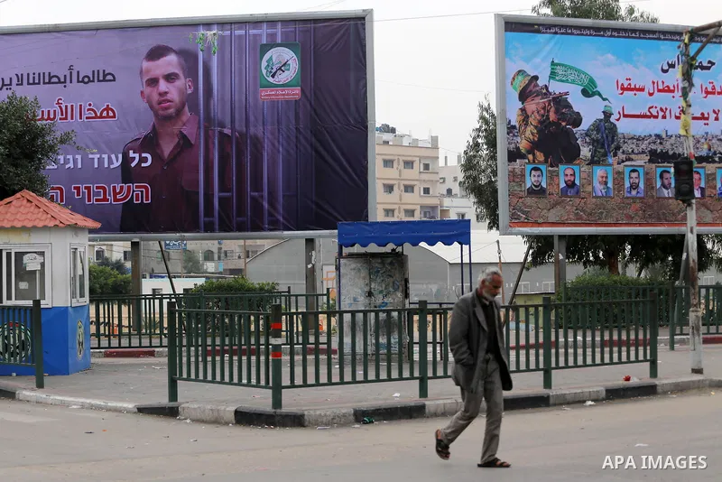 A Palestinian man walks past a billboard bearing a portrait of slain Israeli soldier Oron Shaul in Gaza City on December 29, 2017. The writing in Arabic reads: ''As long as our heroes don't see freedom and light: This ca...