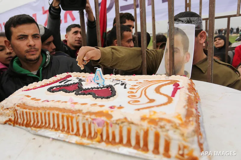 A Palestinian man playing the role of Israeli soldier Oron Shaul is seen in a mock jail as he tries to participate in a birthday party, during a rally in solidarity with Palestinian prisoners held in Israeli jails, in th...