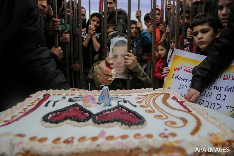 A Palestinian man playing the role of Israeli soldier Oron Shaul is seen in a mock jail as he tries to participate in a birthday party, during a rally in solidarity with Palestinian prisoners held in Israeli jails, in th...