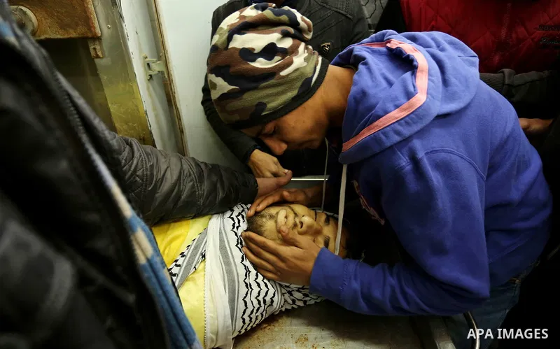 Relatives of Palestinian Jamal Mesleh, 21, who died of his injuries during clashes with Israeli security forces on Friday mourn over his body at a hospital morgue, in Dair Al Balah in the central Gaza Strip December 30,...