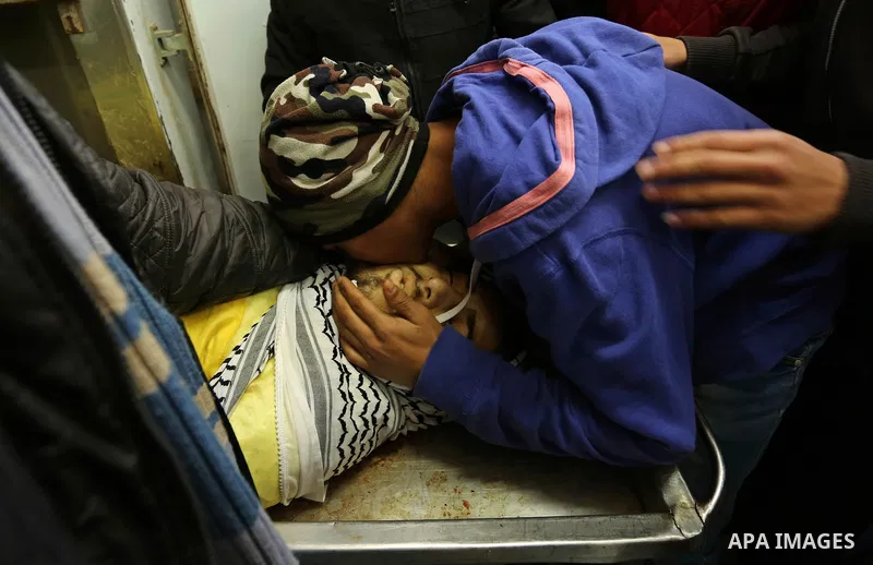 Relatives of Palestinian Jamal Mesleh, 21, who died of his injuries during clashes with Israeli security forces on Friday mourn over his body at a hospital morgue, in Dair Al Balah in the central Gaza Strip December 30,...