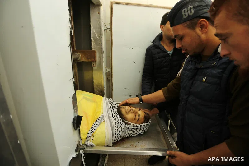 Relatives of Palestinian Jamal Mesleh, 21, who died of his injuries during clashes with Israeli security forces on Friday mourn over his body at a hospital morgue, in Dair Al Balah in the central Gaza Strip December 30,...