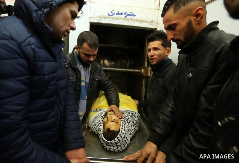 Relatives of Palestinian Jamal Mesleh, 21, who died of his injuries during clashes with Israeli security forces on Friday mourn over his body at a hospital morgue, in Dair Al Balah in the central Gaza Strip December 30,...