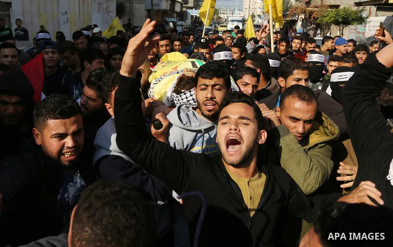 Mourners carry the body of Palestinian Jamal Mesleh, 21, who died of his injuries during clashes with Israeli security forces on Friday, during his funeral in the al-Maghazi refugee camp in the central Gaza Strip Decembe...