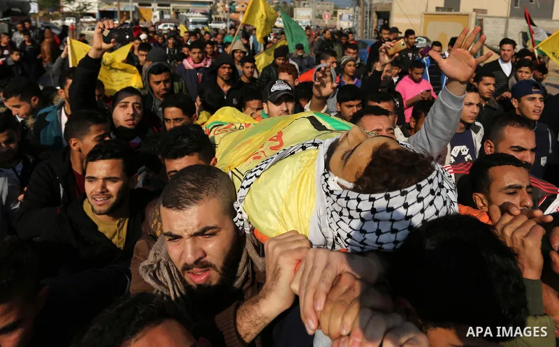 Mourners carry the body of Palestinian Jamal Mesleh, 21, who died of his injuries during clashes with Israeli security forces on Friday, during his funeral in the al-Maghazi refugee camp in the central Gaza Strip Decembe...