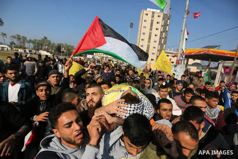 Mourners carry the body of Palestinian Jamal Mesleh, 21, who died of his injuries during clashes with Israeli security forces on Friday, during his funeral in the al-Maghazi refugee camp in the central Gaza Strip Decembe...