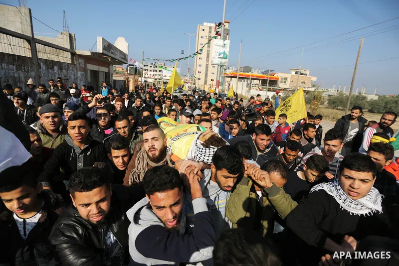 Mourners carry the body of Palestinian Jamal Mesleh, 21, who died of his injuries during clashes with Israeli security forces on Friday, during his funeral in the al-Maghazi refugee camp in the central Gaza Strip Decembe...