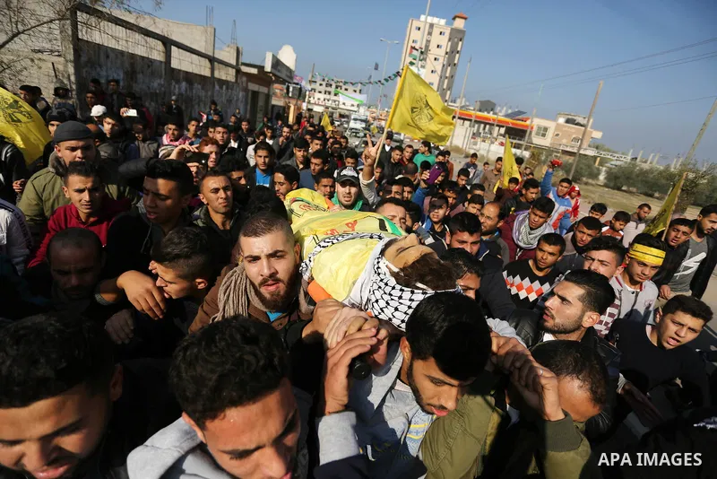 Mourners carry the body of Palestinian Jamal Mesleh, 21, who died of his injuries during clashes with Israeli security forces on Friday, during his funeral in the al-Maghazi refugee camp in the central Gaza Strip Decembe...