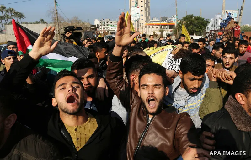 Mourners carry the body of Palestinian Jamal Mesleh, 21, who died of his injuries during clashes with Israeli security forces on Friday, during his funeral in the al-Maghazi refugee camp in the central Gaza Strip Decembe...