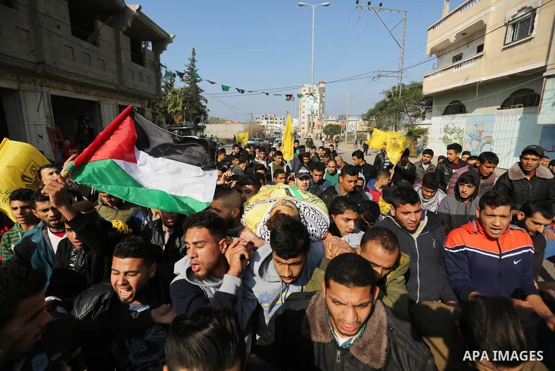 Mourners carry the body of Palestinian Jamal Mesleh, 21, who died of his injuries during clashes with Israeli security forces on Friday, during his funeral in the al-Maghazi refugee camp in the central Gaza Strip Decembe...