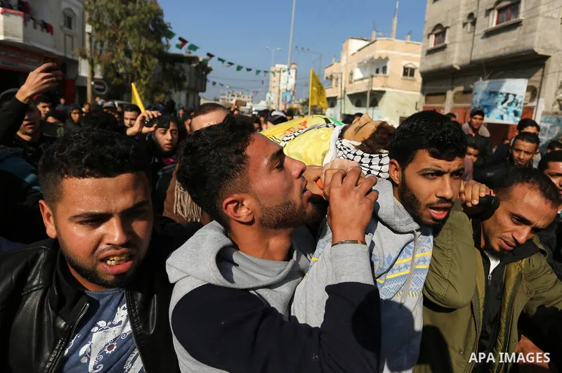 Mourners carry the body of Palestinian Jamal Mesleh, 21, who died of his injuries during clashes with Israeli security forces on Friday, during his funeral in the al-Maghazi refugee camp in the central Gaza Strip Decembe...
