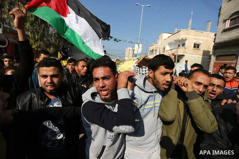 Mourners carry the body of Palestinian Jamal Mesleh, 21, who died of his injuries during clashes with Israeli security forces on Friday, during his funeral in the al-Maghazi refugee camp in the central Gaza Strip Decembe...