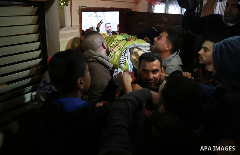 Mourners carry the body of Palestinian Jamal Mesleh, 21, who died of his injuries during clashes with Israeli security forces on Friday, during his funeral in the al-Maghazi refugee camp in the central Gaza Strip Decembe...