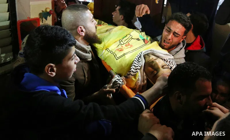 Mourners carry the body of Palestinian Jamal Mesleh, 21, who died of his injuries during clashes with Israeli security forces on Friday, during his funeral in the al-Maghazi refugee camp in the central Gaza Strip Decembe...