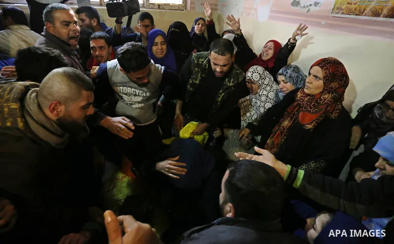 Mourners carry the body of Palestinian Jamal Mesleh, 21, who died of his injuries during clashes with Israeli security forces on Friday, during his funeral in the al-Maghazi refugee camp in the central Gaza Strip Decembe...