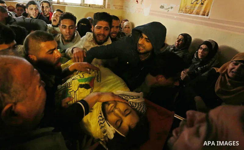 Mourners carry the body of Palestinian Jamal Mesleh, 21, who died of his injuries during clashes with Israeli security forces on Friday, during his funeral in the al-Maghazi refugee camp in the central Gaza Strip Decembe...
