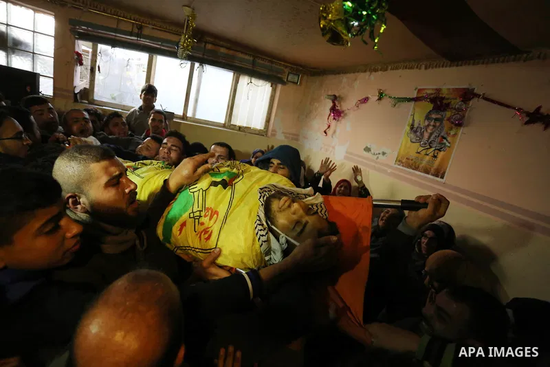 Mourners carry the body of Palestinian Jamal Mesleh, 21, who died of his injuries during clashes with Israeli security forces on Friday, during his funeral in the al-Maghazi refugee camp in the central Gaza Strip Decembe...