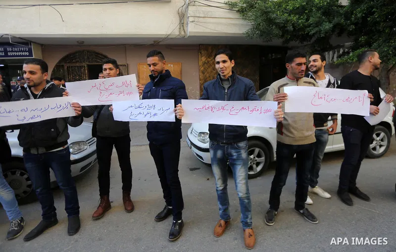 Palestinian youths hold banners during a protest demanding to open the Rafah crossing, in Gaza city on December 31, 2017. Photo by Mohammed Asad