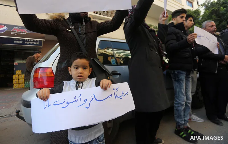 Palestinian youths hold banners during a protest demanding to open the Rafah crossing, in Gaza city on December 31, 2017. Photo by Mohammed Asad