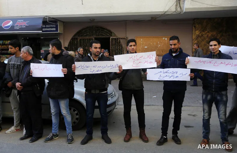 Palestinian youths hold banners during a protest demanding to open the Rafah crossing, in Gaza city on December 31, 2017. Photo by Mohammed Asad