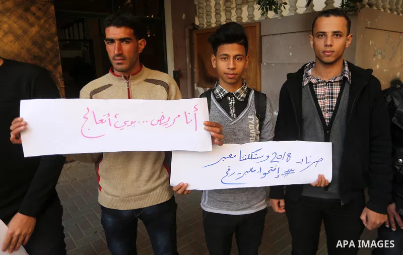 Palestinian youths hold banners during a protest demanding to open the Rafah crossing, in Gaza city on December 31, 2017. Photo by Mohammed Asad