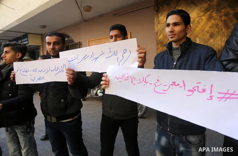 Palestinian youths hold banners during a protest demanding to open the Rafah crossing, in Gaza city on December 31, 2017. Photo by Mohammed Asad
