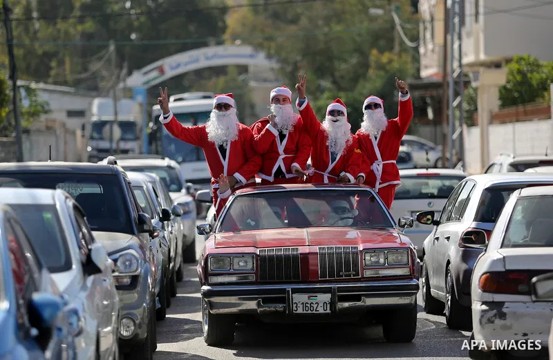 Palestinians dressed as Santa Claus ride a red car to welcome the new year, in the streets of Gaza City, on December 31, 2017. New Year's Eve revellers. Photo by Ashraf Amra