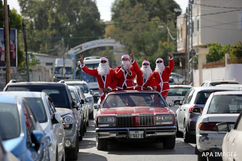 Palestinians dressed as Santa Claus ride a red car to welcome the new year, in the streets of Gaza City, on December 31, 2017. New Year's Eve revellers. Photo by Ashraf Amra