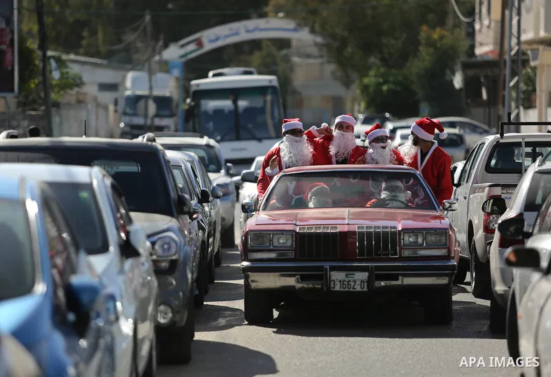 Palestinians dressed as Santa Claus ride a red car to welcome the new year, in the streets of Gaza City, on December 31, 2017. New Year's Eve revellers. Photo by Ashraf Amra