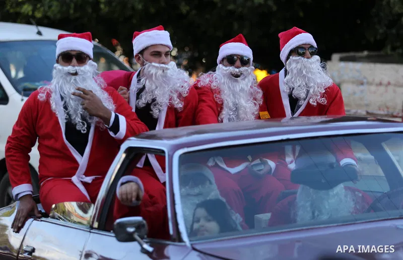 Palestinians dressed as Santa Claus ride a red car to welcome the new year, in the streets of Gaza City, New Year's Eve revellers on December 31, 2017. Photo by Ashraf Amra