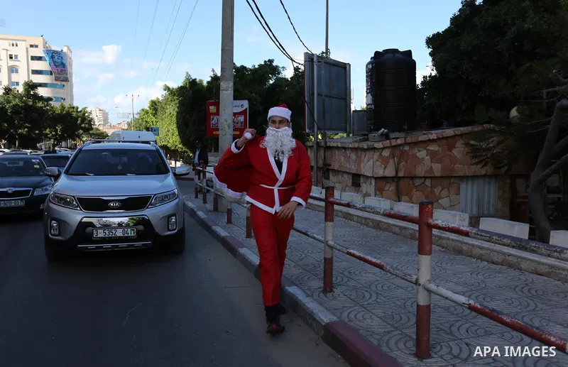 A Palestinian dressed as Santa Claus celebrates to welcome the new year, in the streets of Gaza City, New Year's Eve revellers on December 31, 2017. Photo by Ashraf Amra