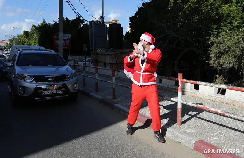 A Palestinian dressed as Santa Claus celebrates to welcome the new year, in the streets of Gaza City, New Year's Eve revellers on December 31, 2017. Photo by Ashraf Amra