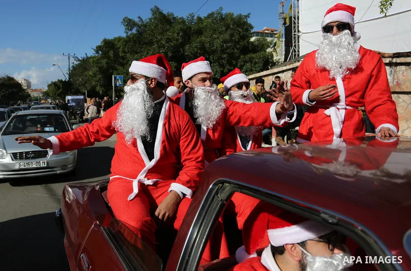 Palestinians dressed as Santa Claus ride a red car to welcome the new year, in the streets of Gaza City, New Year's Eve revellers on December 31, 2017. Photo by Ashraf Amra