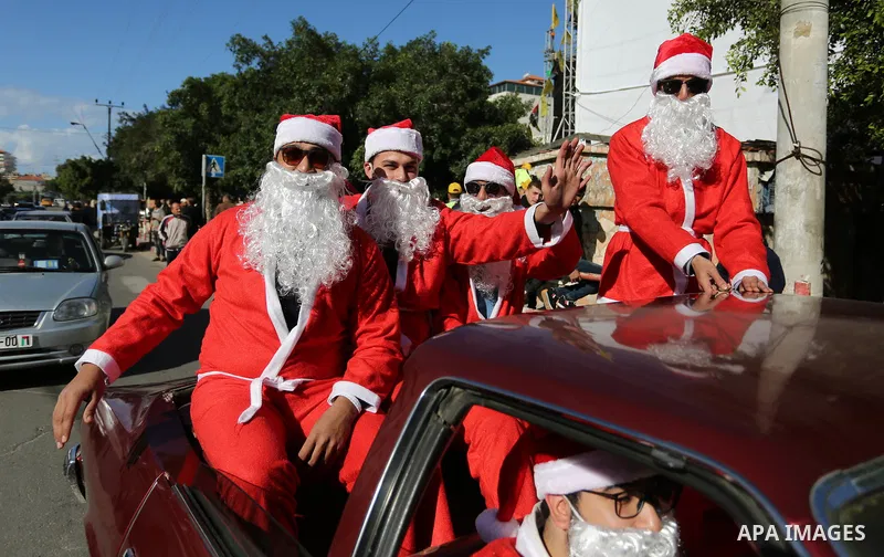 Palestinians dressed as Santa Claus ride a red car to welcome the new year, in the streets of Gaza City, New Year's Eve revellers on December 31, 2017. Photo by Ashraf Amra