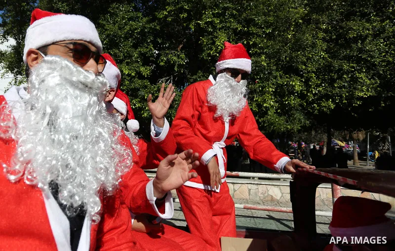 Palestinians dressed as Santa Claus ride a red car to welcome the new year, in the streets of Gaza City, New Year's Eve revellers on December 31, 2017. Photo by Ashraf Amra