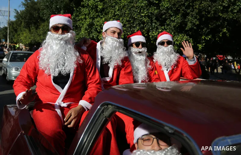 Palestinians dressed as Santa Claus ride a red car to welcome the new year, in the streets of Gaza City, New Year's Eve revellers on December 31, 2017. Photo by Ashraf Amra