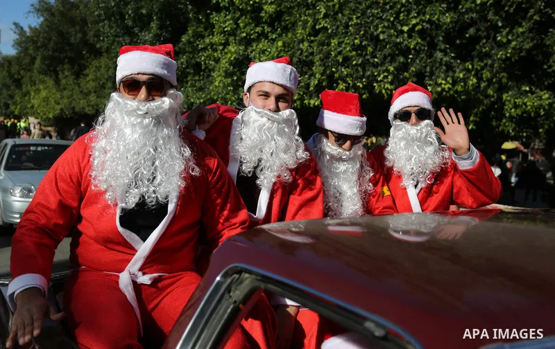 Palestinians dressed as Santa Claus ride a red car to welcome the new year, in the streets of Gaza City, New Year's Eve revellers on December 31, 2017. Photo by Ashraf Amra