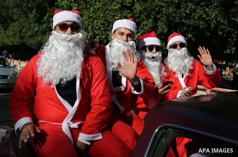 Palestinians dressed as Santa Claus ride a red car to welcome the new year, in the streets of Gaza City, New Year's Eve revellers on December 31, 2017. Photo by Ashraf Amra