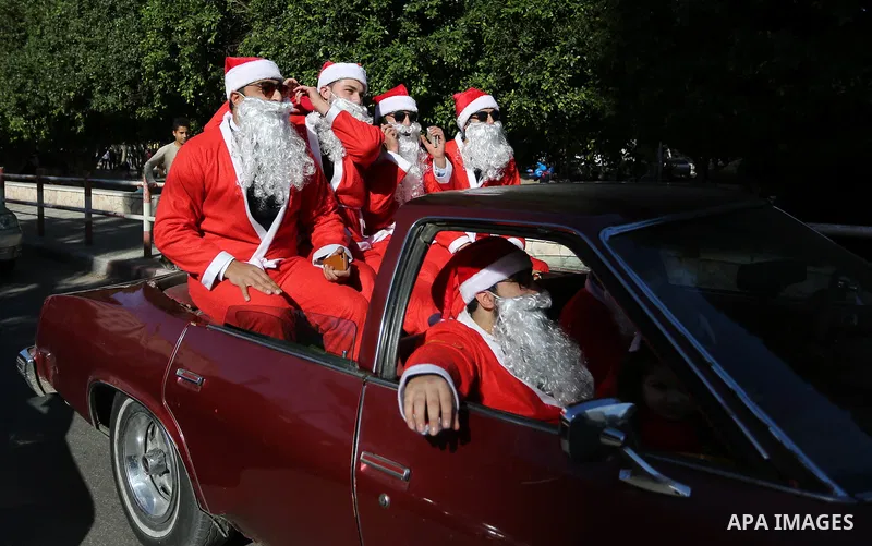 Palestinians dressed as Santa Claus ride a red car to welcome the new year, in the streets of Gaza City, New Year's Eve revellers on December 31, 2017. Photo by Ashraf Amra