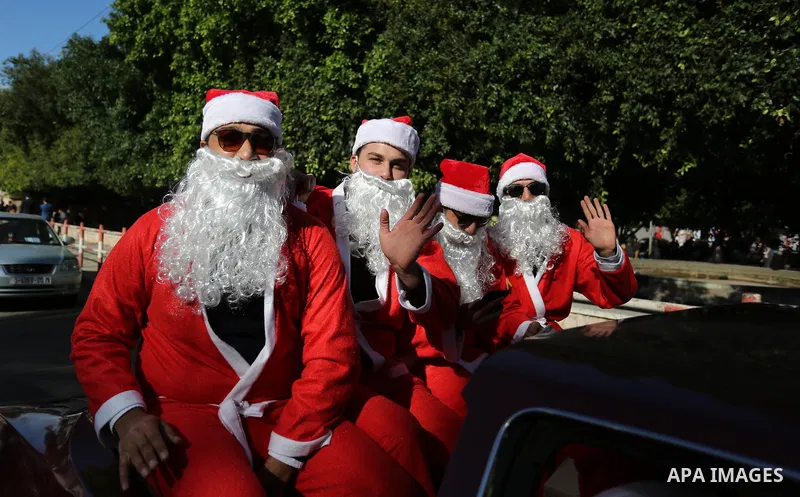 Palestinians dressed as Santa Claus ride a red car to welcome the new year, in the streets of Gaza City, New Year's Eve revellers on December 31, 2017. Photo by Ashraf Amra